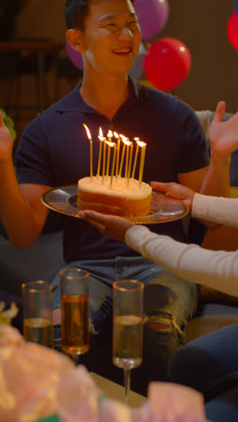 Vertikales-Video-Einer-Multikulturellen-Gruppe,-Die-Zu-Hause-Den-Geburtstag-Von-Freunden-Mit-Kuchen-Und-Kerzen-Auf-Einer-Party-Feiert